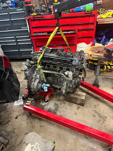 Engine on an engine hoist mid-swap in the Powertrain Pros home garage